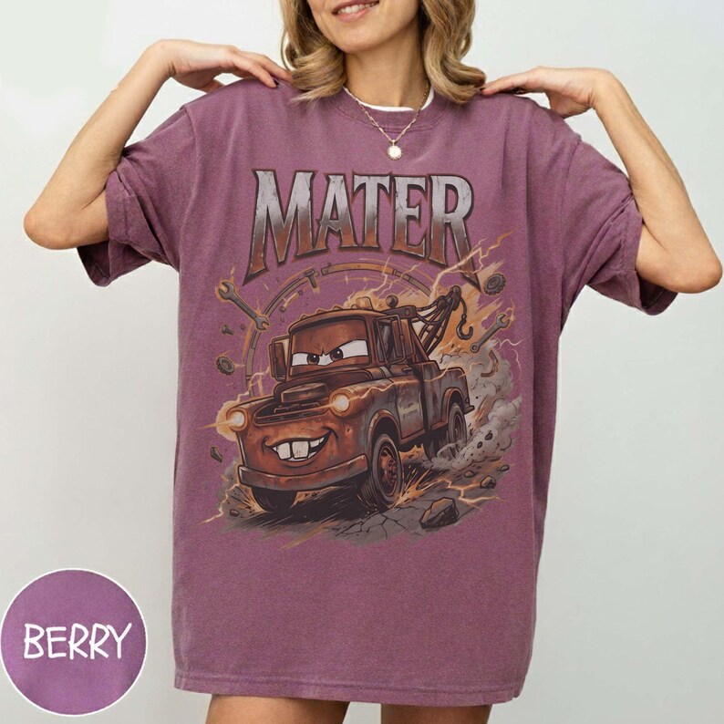 Puede incluir: Camiseta color bayas con un dise&ntilde;o de Mate de la pel&iacute;cula Cars. La palabra "MATER" est&aacute; impresa en la parte superior. El dise&ntilde;o incluye rayos, herramientas y una ilustraci&oacute;n de gr&uacute;a. La camiseta tiene mangas cortas.
