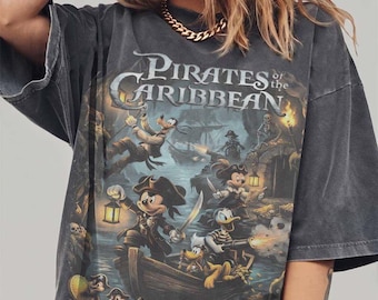 Puede incluir: Una camiseta gris carbón de corte oversize con un estampado gráfico de personajes de Disney vestidos de piratas de Piratas del Caribe. El diseño incluye a Mickey Mouse, el Pato Donald, Goofy y Pluto en un barco con linternas y tesoros.