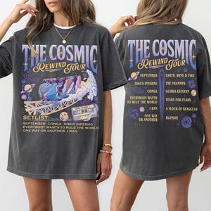 May include: Dark gray t-shirt with a graphic design for "The Cosmic Rewind Tour." The front features a colorful design with a roller coaster and the text "The Cosmic Rewind Tour." The back lists the tour's setlist and dates.
