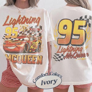 Może przedstawiać: Kremowa koszulka z grafiką Zygzaka McQueena z filmu Auta. Prz&oacute;d przedstawia postać z napisem "Lightning 95 McQueen". Tył pokazuje numer 95 z płomieniami i "Lightning McQueen."