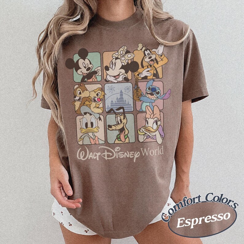 May include: Espresso-colored t-shirt featuring a grid of Disney characters, including Mickey Mouse, Minnie Mouse, and Goofy. The shirt has the words "Walt Disney World" printed below the grid. The shirt is a Comfort Colors brand.