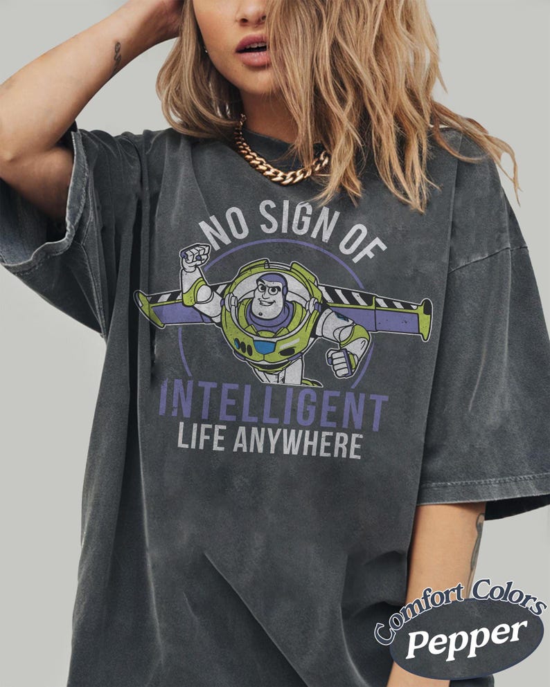 May include: Dark gray t-shirt with a graphic of Buzz Lightyear and the text "NO SIGN OF INTELLIGENT LIFE ANYWHERE." The shirt is a Comfort Colors Pepper tee.