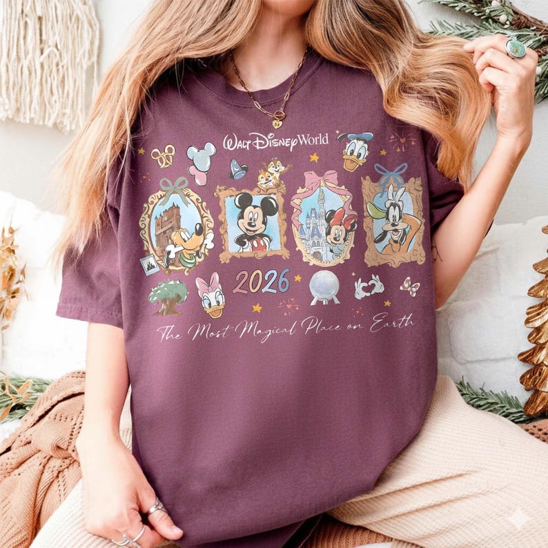 May include: A maroon t-shirt featuring a Walt Disney World design. The design includes framed images of Disney characters like Mickey Mouse, Donald Duck, and Minnie Mouse, along with the year 2026 and the phrase "The Most Magical Place on Earth."