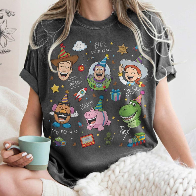 May include: Dark gray t-shirt featuring cartoon characters Woody, Buzz Lightyear, Jessie, Mr. Potato Head, and Rex. The shirt has a distressed look and includes the text "Buzz Lightyear" and character names.