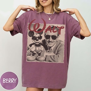Pu&ograve; includere: Una t-shirt a maniche corte color bacca con una stampa grafica di Walt Disney e Topolino, entrambi con occhiali da sole. Il testo "Walt" &egrave; stampato in un carattere rosso stilizzato sopra le figure. La maglietta ha un girocollo.