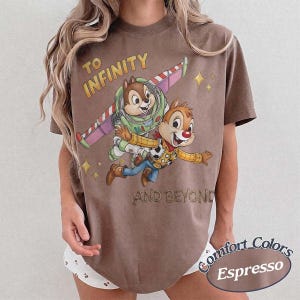 Puede incluir: Camiseta color espresso con un gr&aacute;fico de Chip y Chop como Buzz Lightyear y Woody, con el texto "TO INFINITY AND BEYOND." La camiseta es de la marca Comfort Colors.