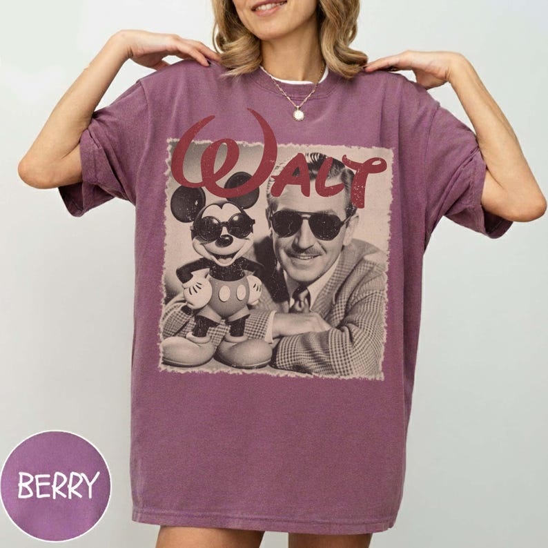 Puede incluir: Camiseta color bayas con un gr&aacute;fico vintage de Walt Disney y Mickey Mouse con gafas de sol. La palabra "WALT" est&aacute; impresa encima de la imagen en una fuente roja estilizada. La camiseta tiene un corte holgado.