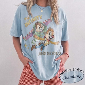 Puede incluir: Camiseta azul claro con un gr&aacute;fico de Chip y Chop como Buzz Lightyear y Woody de Toy Story, con el texto "To Infinity and Beyond". La camiseta es un Comfort Colors Chambray.