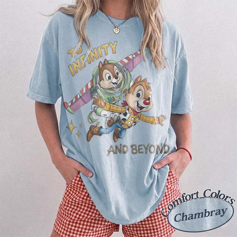 Puede incluir: Camiseta azul claro con un gr&aacute;fico de Chip y Chop como Buzz Lightyear y Woody de Toy Story, con el texto "To Infinity and Beyond". La camiseta es un Comfort Colors Chambray.