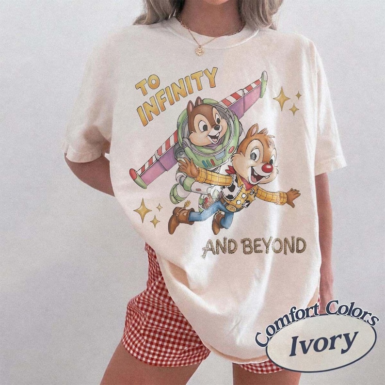 Puede incluir: Camiseta de color marfil con un gr&aacute;fico de Chip y Chop como Buzz Lightyear y Woody con el texto "TO INFINITY AND BEYOND". La camiseta tiene una etiqueta Comfort Colors.