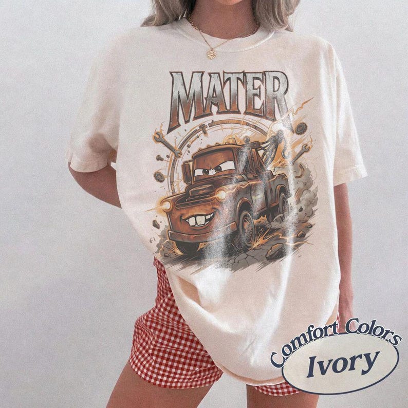 Puede incluir: Camiseta de color marfil con un gr&aacute;fico del personaje Mater de la pel&iacute;cula Cars. El dise&ntilde;o incluye la palabra "MATER" en una fuente desgastada sobre el personaje. La camiseta es de la marca Comfort Colors.