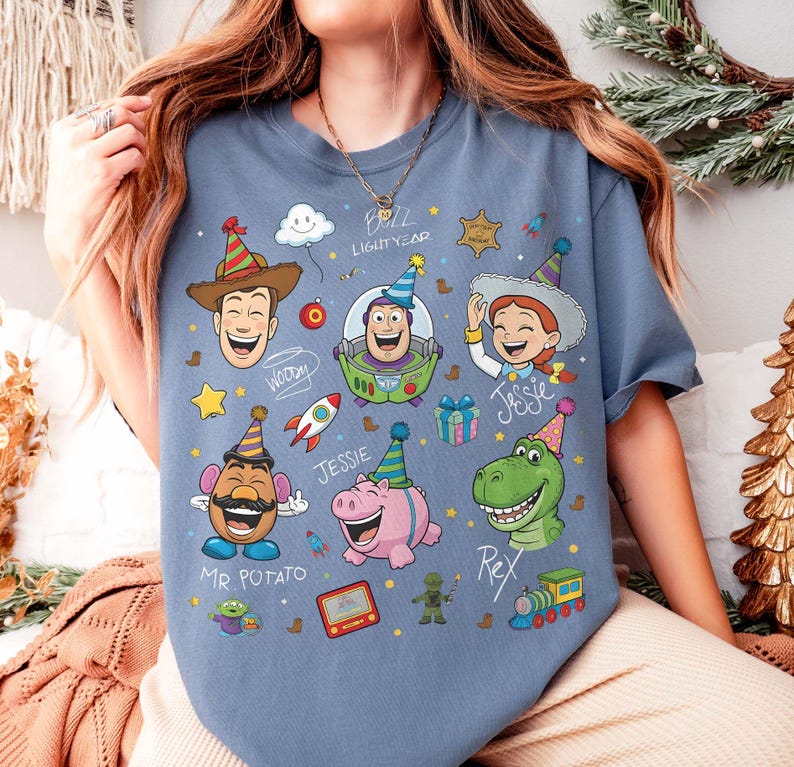 May include: Blue t-shirt featuring cartoon characters Woody, Buzz Lightyear, Jessie, Mr. Potato Head, Rex, and Hamm. The design includes party hats, a rocket, and the text "Buzz Lightyear".