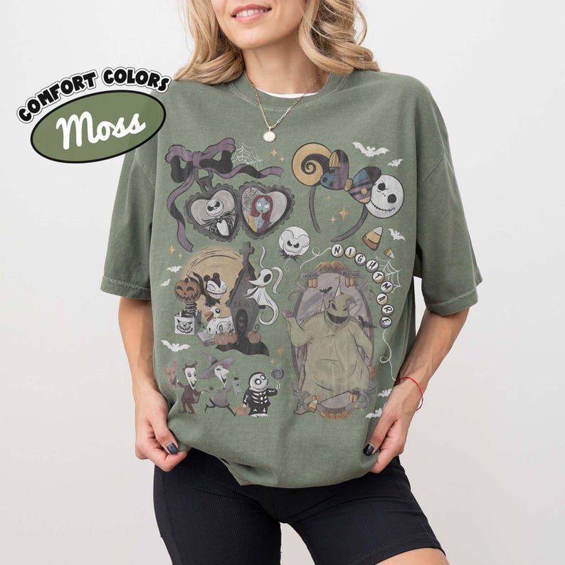 May include: A moss green short-sleeve t-shirt featuring a graphic print of characters and icons from The Nightmare Before Christmas, including Jack Skellington, Sally, Oogie Boogie, and Zero, with the text COMFORT COLORS Moss in the upper left corner.