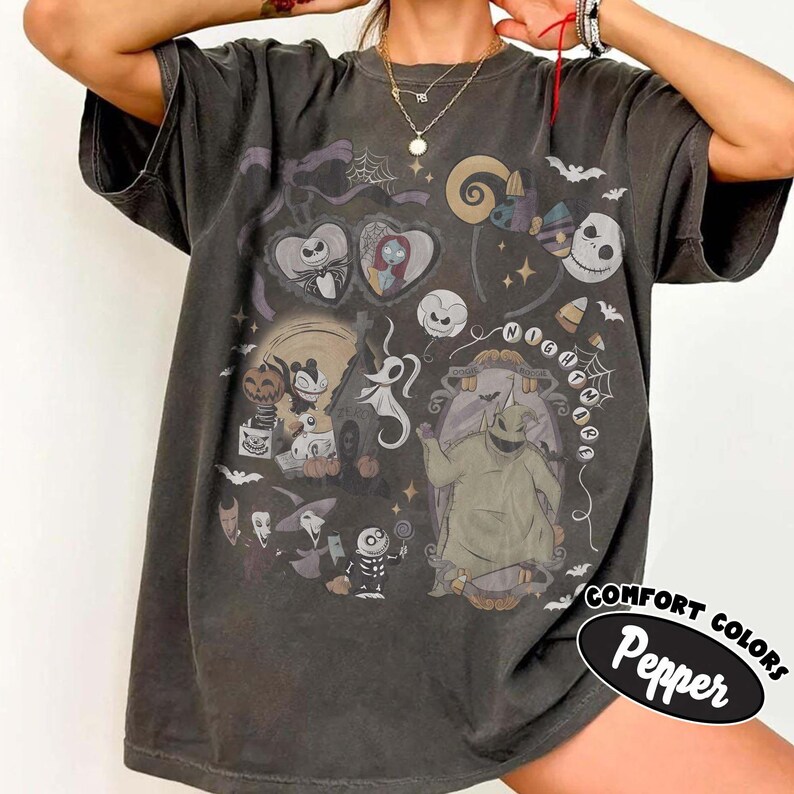 May include: A charcoal gray short-sleeve t-shirt featuring a graphic print of characters from The Nightmare Before Christmas, including Jack Skellington, Sally, and Oogie Boogie, surrounded by spiderwebs, bats, and stars in muted tones.