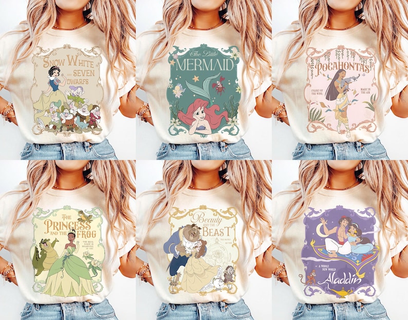 May include: A collection of six cream-colored t-shirts, each featuring a different Disney princess design. The designs include Snow White, Ariel, Pocahontas, Tiana, Belle, and Jasmine. Each design is framed with decorative borders and text.
