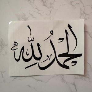 May include: Black vinyl decal featuring Arabic calligraphy. The script reads "Alhamdulillah" in a stylized font. The decal is on a white background, suitable for application on various surfaces.