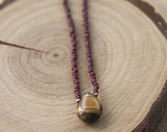 May include: A burgundy beaded necklace with a teardrop-shaped tiger's eye pendant.
