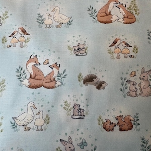 May include: A light blue fabric featuring a repeating pattern of woodland animals including foxes, rabbits, hedgehogs, ducks, mice, squirrels, and birds, interspersed with small green plants, butterflies, and tiny star-shaped accents.