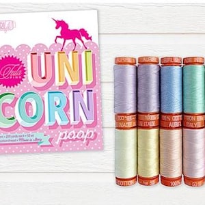 May include: A collection of colorful sewing thread spools next to a card with the words "UNICORN poop". The thread spools are in shades of purple, blue, green, and pink. The card has a pink unicorn graphic.