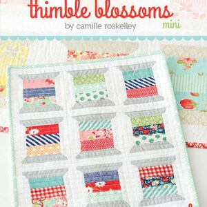 May include: A mini quilt featuring nine colorful spools of thread, each with a unique fabric pattern in shades of red, blue, green, and pink. The quilt is bordered with a light green and white pattern. The text "thimble blossoms" is at the top.