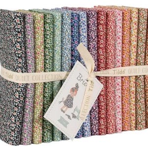 May include: A bundle of floral fabric squares from the Tilda Quilt Collection. The fabric features small, colorful flower patterns on various backgrounds. A cream-colored ribbon with the text "Tilda Quilt Collection" wraps around the bundle. A tag with a drawing of a girl is attached.