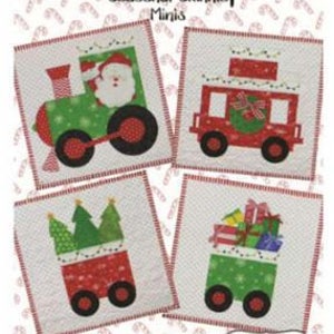 May include: A festive quilt pattern titled "North Pole Express" featuring four square designs of Christmas train cars. Each car is red or green with black wheels, carrying Santa, gifts, and Christmas trees. The background is white with a candy cane pattern.
