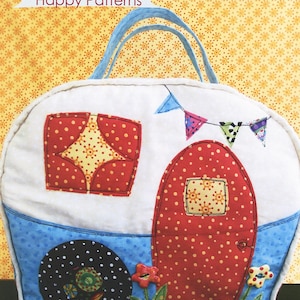 May include: A handmade Happy Camper Bag, a whimsical tote bag with a camper design. The bag features a white body, red polka-dot door and window, blue accents, and a banner of colorful flags. The bag has a light blue handle.