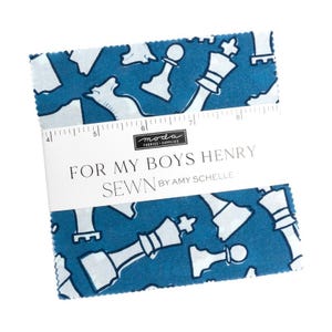 May include: A stack of fabric squares with a blue background and white chess piece pattern. The fabric is labeled "FOR MY BOYS HENRY SEWN BY AMY SCHELLE". A ruler is printed on the fabric.