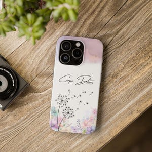 Op de afbeelding: Een witte telefoonhoes met een aquarel achtergrond en een paardenbloem ontwerp. De hoes heeft een zwarte inscriptie met de tekst "Carpe Diem".