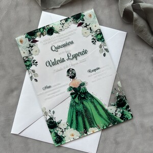 Op de afbeelding: Een transparante acryl Quincea&ntilde;era-uitnodiging met een groen en wit bloemenontwerp. De uitnodiging toont een tekening van een meisje in een groene jurk met een witte strik. De tekst op de uitnodiging luidt "El Se&ntilde;or y la Se&ntilde;ora los invitan a celebrar Quincea&ntilde;era de su hija Valeria Lupercio".