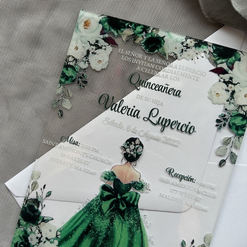 Op de afbeelding: Een uitnodiging voor een Quincea&ntilde;era met een groen en wit bloemenontwerp. De uitnodiging toont een groene jurk met een witte strik en een bloemenkroon. De tekst op de uitnodiging luidt "Quincea&ntilde;era de su hija Valeria Lupercio, S&aacute;bado, 6 de Agosto 2022".