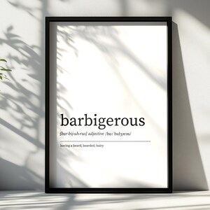 Op de afbeelding: Een zwart omkaderde print met het woord "barbigerous" in een zwarte, vette letter. De uitspraak en definitie zijn ook opgenomen. De achtergrond is wit. Schaduwen vallen op het beeld.