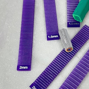 May include: Five purple plastic tools with ridges for polymer clay. The tools are labeled with measurements in millimeters: 2mm, 3mm, 5mm, 1.5mm, and 4.5mm.