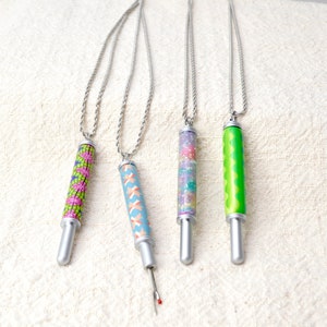 Peut inclure: Quatre colliers avec des d&eacute;coud-vite et des cha&icirc;nes argent&eacute;es. Les d&eacute;coud-vite pr&eacute;sentent des motifs color&eacute;s : un motif g&eacute;om&eacute;trique rose et vert, un motif crois&eacute; bleu et p&ecirc;che, un motif de confettis scintillants et un motif vert ondul&eacute;. Les d&eacute;coud-vite sont argent&eacute;s.