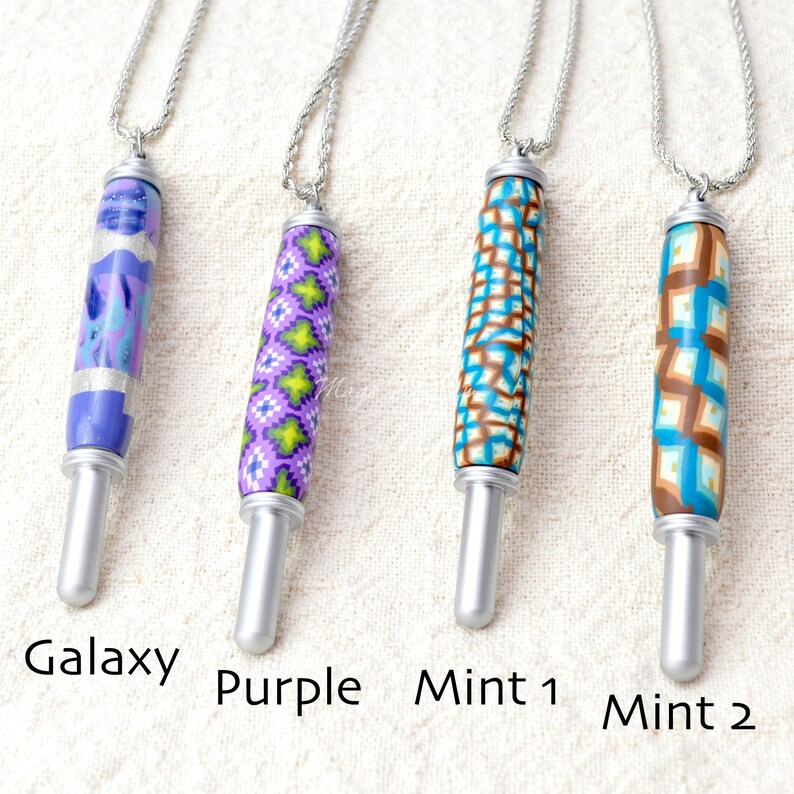 May include: Four handmade pendant necklaces with silver chains. The pendants are cylindrical with colorful patterns: a galaxy design, a purple geometric pattern, a turquoise and brown pattern, and a turquoise and brown pattern. The text on the image reads "Galaxy", "Purple", "Mint 1", and "Mint 2".