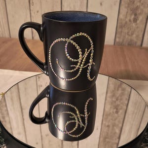 May include: Black ceramic mug with a blue interior and a single initial "A" in iridescent rhinestones.