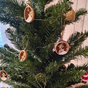 May include: A decorated Christmas tree with handmade walnut shell ornaments. The ornaments feature painted designs of angels and reindeer. The tree is green and has small white lights, creating a festive display.
