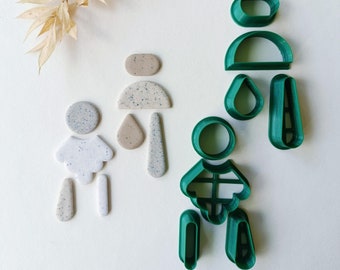 May include: A set of green plastic cookie cutters shaped like a family. The cutters include a father, mother, and child. The cutters are on a white background.