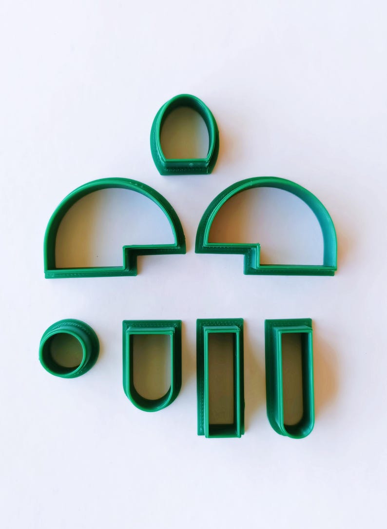 May include: A set of seven green plastic cookie cutters shaped like different windows and arches.