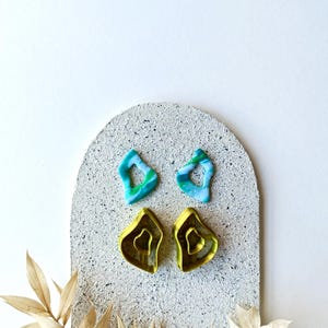 Peut inclure: Un ensemble de quatre boucles d'oreilles en argile polymère. Deux boucles d'oreilles sont vertes et jaunes, et deux sont bleues et vertes.