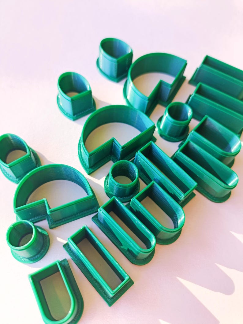 May include: A set of 14 green plastic cookie cutters in various shapes, including circles, squares, rectangles, and arches.