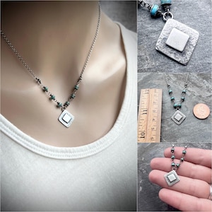 May include: Silver necklace with a diamond-shaped pendant and turquoise beads. The pendant has a textured surface with a smaller square in the center. The necklace is shown on a person wearing a white shirt.