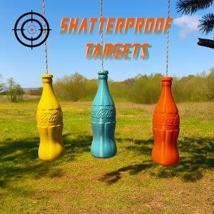 Puede incluir: Tres dianas irrompibles y coloridas con forma de botellas de refresco cuelgan de cuerdas. Las dianas son amarillas, turquesas y naranjas, con el logotipo de Coca-Cola. Las palabras "SHATTERPROOF TARGETS" están arriba, contra un cielo azul.