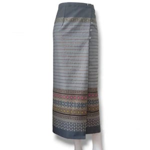 以下が含まれることがあります： ボタン留めのグレーとブラウンの柄のラップスカート。スカートはピンク、イエロー、ブルーのボーダーで幾何学模様になっている。