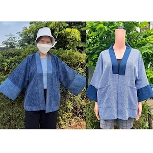 May include: A blue open-front jacket featuring a textured fabric with a color-blocked design. The garment has wide sleeves, a solid dark blue collar, and two front pockets. The jacket displays varying shades of blue in a patchwork-style pattern.