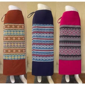 以下が含まれることがあります： 幾何学模様の長いスカートが3枚。スカートは茶色、紺色、ピンク。それぞれウエストとリボンが付いています。