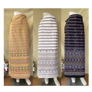 以下が含まれることがあります： 異なるパターンを持つ3つのロングスカート。左側のスカートは薄い茶色で、下部にカラフルな幾何学模様があります。中央のスカートは白で、グレーと白のストライプ模様と、下部にグレーの幾何学模様があります。右側のスカートは黒で、グレーと白のストライプ模様と、下部にカラフルな幾何学模様があります。