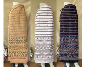 May include: Three long skirts with different patterns. The skirt on the left is a light brown with a colorful geometric pattern at the bottom. The middle skirt is white with a gray and white striped pattern and a gray geometric pattern at the bottom. The skirt on the right is black with a gray and white striped pattern and a colorful geometric pattern at the bottom.