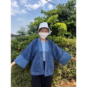 May include: A blue denim-style kimono jacket featuring a textured, mottled wash pattern with contrasting lighter blue cuffs and collar trim, worn over a light blue top and black trousers, paired with a white bucket hat and a white face mask.