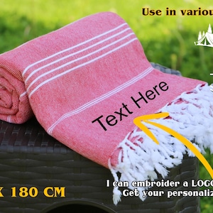 May include: A rolled red towel with white stripes and fringe, measuring 39 inches by 71 inches. The towel is displayed on a dark brown surface, with text that says "Text Here". The image also includes icons for various locations.